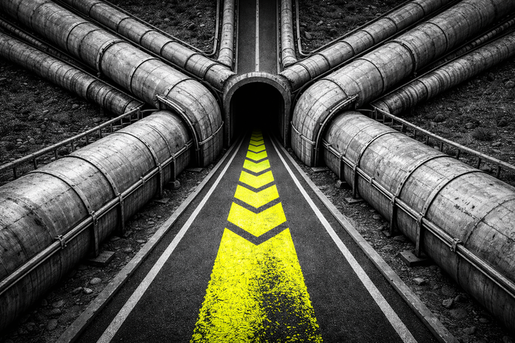 Top-down black and white aerial view of industrial pipelines converging into a single narrow tunnel, marked by an acid yellow safety stripe highlighting the bottleneck
