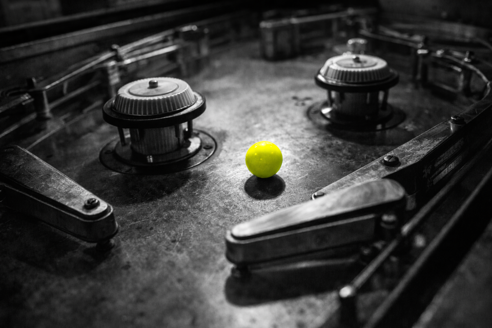 A machine built for momentum, paused mid-trajectory. One acid-yellow ball, caught between bumpers, waiting for the next force to make the system move